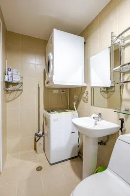 a small bathroom with a white refrigerator and a sink at Central Stay w King bed near Greenbelt 55-In TV in Manila