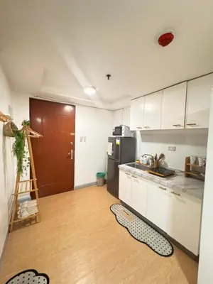 a kitchen with white cabinets and a wooden floor at Coziey Inn in Manila