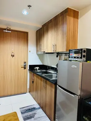 a kitchen with wooden cabinets and a refrigerator at MOA Shore 3 One Bedroom Family Suite with Balcony in Manila