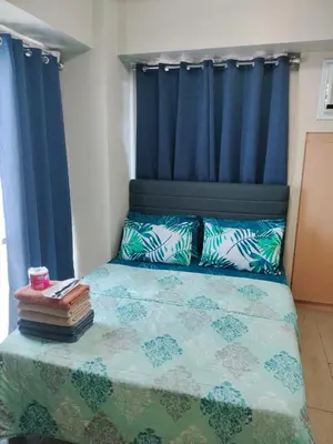 a bedroom with a bed with blue curtains at Rooms in Pasay City At Two Palm Tree Villas in Manila