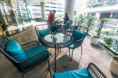 a patio with tables and chairs and people on a balcony at Modern One BR Makati Condo Swim Gym Parking Netflix Fast 2428 in Manila