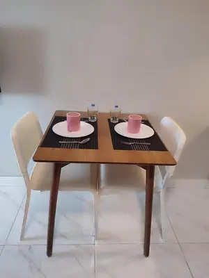 a wooden table with two chairs and two cups and plates at Facing Pool w Balcony MOA BP1741 in Manila