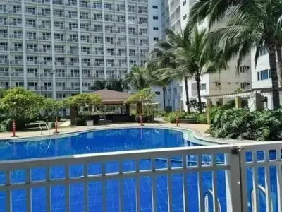 a blue swimming pool in front of a large building at Staycation in Alabang Branch B in Manila