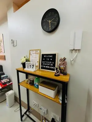 a black clock on a wall above a shelf at Meteoria Staycation in Manila