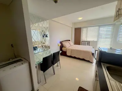 a bedroom with a bed and a table and chairs at Elegant Suite with Balcony l Free wifi and netflix I Across NAIA T3 Airport in Manila