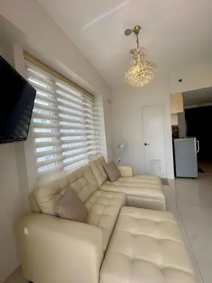 a living room with a white couch and a television at Elegant Suite with Balcony l Free wifi and netflix I Across NAIA T3 Airport in Manila