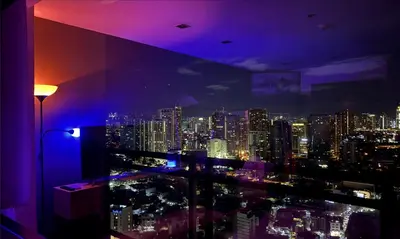a room with a view of a city at night at The Gramercy Residences in Manila