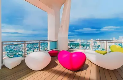 a balcony with white and pink chairs and a view at Aveline Suites Riverline in Manila
