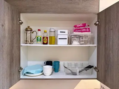 a cupboard filled with dishes and other kitchen items at Prime Location condo near MRT, SM Megamall, BGC! in Manila