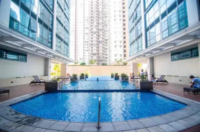 a large swimming pool in a building with tall buildings at ONE UPTOWN RESIDENCE BGC 2-bed 1BR in Manila