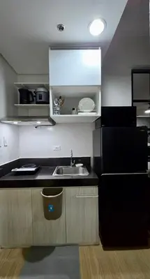 a kitchen with a sink and a black refrigerator at SW Staycation Liam Suite SMDC Hope Residences Beside SM City in Trece Martires