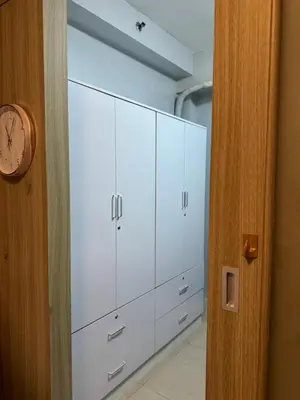 a row of white cabinets in a room with a clock at Cozy home in Manila