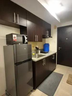 a kitchen with black cabinets and a stainless steel refrigerator at B&C studio in Manila