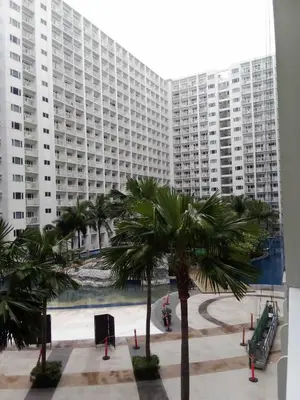 a large building with palm trees in front of it at Shore Residence Tower C2 in Manila