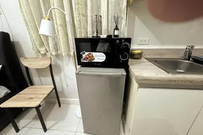 a kitchen with a microwave on top of a refrigerator at KL Studio close to Greenbelt in Manila