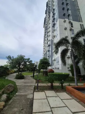 a large apartment building with a sidewalk and palm trees at B&C Studio Kasara Urban Resort Residences in Manila