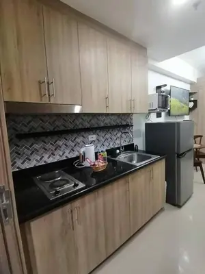 a kitchen with wooden cabinets and a sink and a refrigerator at The Donegal with WI-FI Netflix Parking with fee in Manila