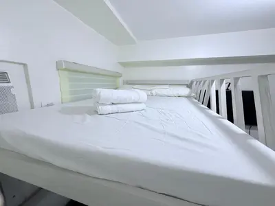 a white bed in a room with towels on it at Michaels Cozy Retreat in Cubao in Manila