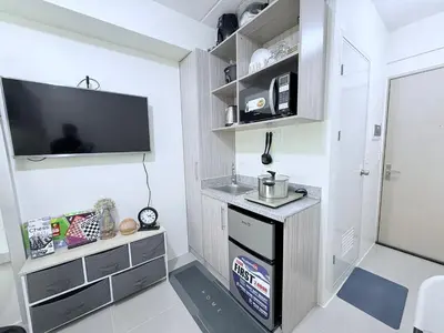 a small kitchen with a sink and a tv on the wall at Michaels Cozy Retreat in Cubao in Manila