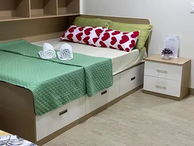 a bedroom with a bed with green and red pillows at DH Suites in Manila