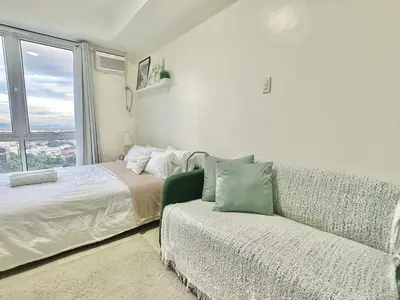 a bedroom with a couch and a bed and a window at Comfy Spot Staycation Studio at Kasara Urban Pasig in Manila