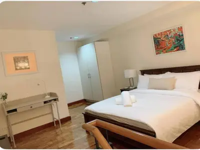 a bedroom with a large bed and a desk at Modern Makati Condo for Rent - City Views Convenience in Manila