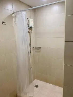 a shower with a white shower curtain in a bathroom at Modern Makati Condo for Rent - City Views Convenience in Manila