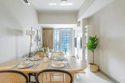 a dining room with a wooden table and chairs at Stylish 2 BR Home with Bathtub and Balcony Uptown BGC in Manila