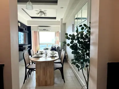 a dining room with a table and chairs and a plant at Modern Luxe 3 BR Home BGC in Manila