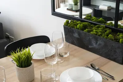 a wooden table with plates and wine glasses on it at Scandi 1 BR Home Golf View BGC in Manila