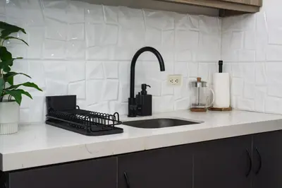 a kitchen counter with a sink and aaucet at Scandi 1 BR Home Golf View BGC in Manila