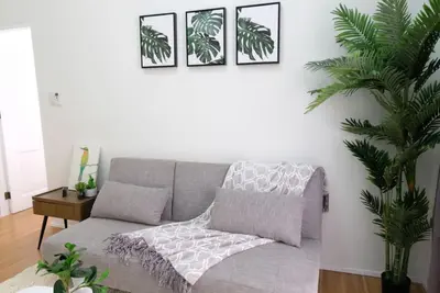 a living room with a gray couch and three pictures on the wall at Golf Penthouse Balcony BGC in Manila