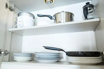 a kitchen shelf with plates and a pan on it at Julias Bright Stylish Condo Balcony in Manila
