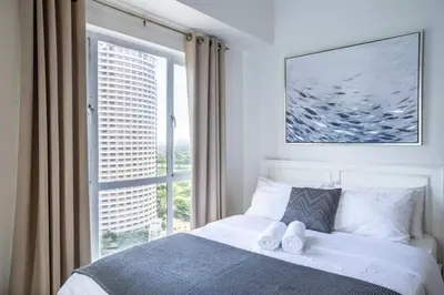 a bedroom with a bed and a large window at Julias Bright Stylish Condo Balcony in Manila
