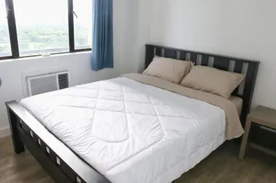 a bedroom with a large bed with a white comforter at Julias Attractive and Cozy Penthouse Golf View in Manila
