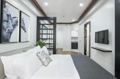a bedroom with a bed and a tv on a wall at Julias Contemporary Apt Balcony and Golf View in Manila