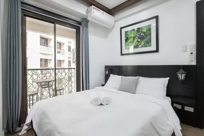 a bedroom with a large white bed and a balcony at Julias Contemporary Apt Balcony and Golf View in Manila
