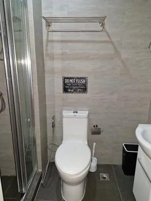 a bathroom with a toilet and a sign on the wall at Comfy Stay 50 mbps Wi-Fi, Smart TV, Netflix in Manila
