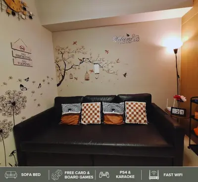 a living room with a black leather couch with pillows at Shore Residences - Near Mall of Asia in Manila