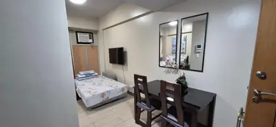 a room with a table and a bed and a mirror at Rqui Condotel Across Terminal 3 in Manila