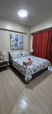 a bedroom with a bed and a red curtain at Rqui Condotel Across Terminal 3 in Manila