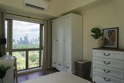 a bedroom with a bed and a large window at Elegant and Modern 2 BR Home Golf Skyline View in Manila