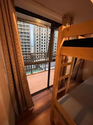 a bedroom with a balcony with a view of a building at Bayport West Naia Residences in Manila