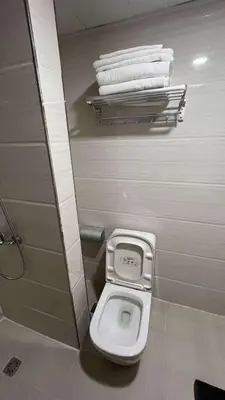 a toilet in a bathroom with towels on a shelf at Bayport West Naia Residences in Manila