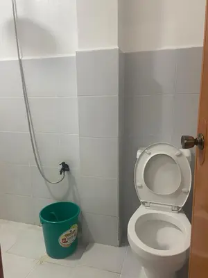 a bathroom with a toilet and a green bucket at Marites Guesthouse in General Trias