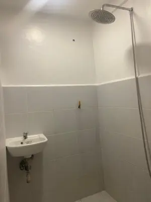 a white bathroom with a sink and a shower at Marites Guesthouse in General Trias