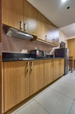 a kitchen with wooden cabinets and a stove top oven at Location perfect staycation with Netflix in Manila