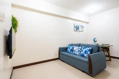 a living room with a blue couch and a tv at 2 bed room in Fairlane Residences Pasig in Manila