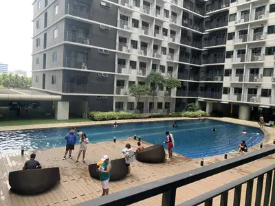 a group of people standing around a swimming pool in a building at Minimalist Big 1BR Pool View MOA Airport in Manila