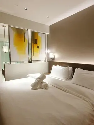 a white bed with a teddy bear laying on it at Novotel Hotel Residences at Acqua- AMOREsuite in Manila